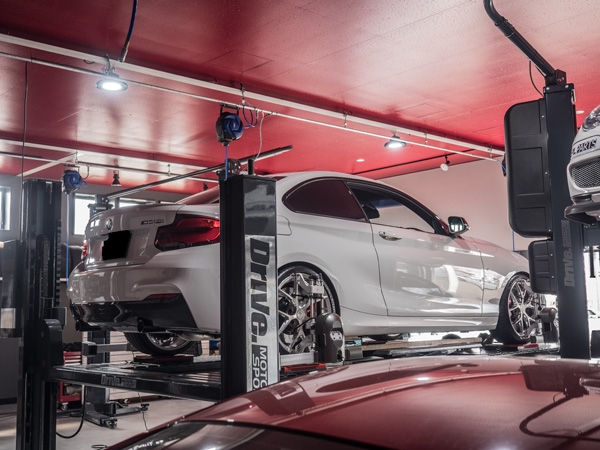 整備工場のリフトに載せられた白いBMWクーペ