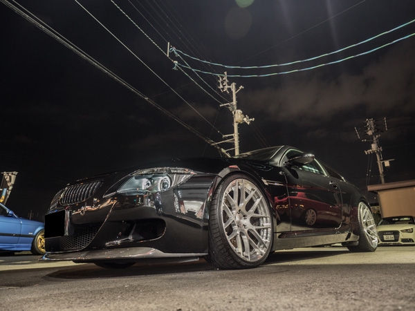 夜の駐車場に停まるカスタムされた黒いBMW M6