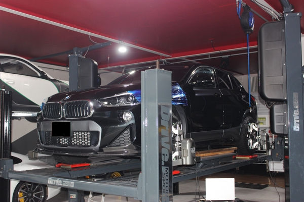整備工場のリフトで持ち上げられた黒いBMW