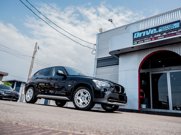 Drive. MOTOR SPORTの店舗前に停車する黒のBMW