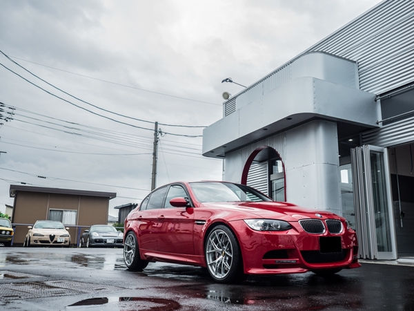 建物の前に停車する赤いBMW M3セダン