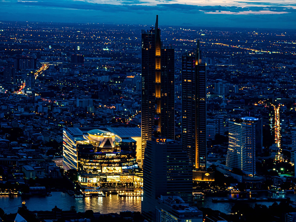 A professional blue-hour photograph of the vast Bangkok skyline from above, with the brightly illuminated Icon Siam mall creating a focal point on the river, showcasing a stunning cityscape.