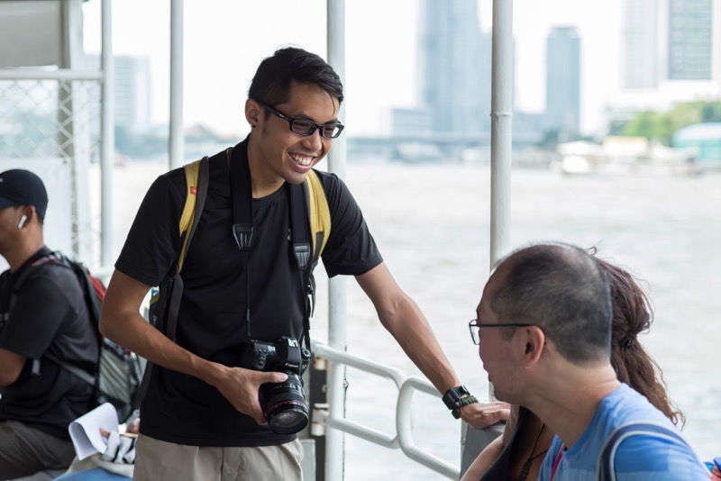 Walk-Talk-Photo photographer chatting with a guest by the Chao Phraya River in Bangkok