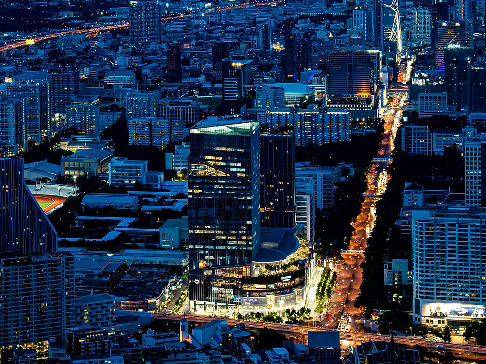A stunning blue-hour aerial photo of the Bangkok skyline, showing a modern skyscraper illuminated against a river of glowing traffic lights, captured on a professional photography tour.