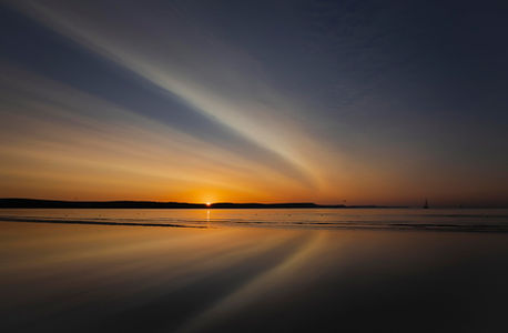 Sunrise over calm water with golden light reflected across the surface
