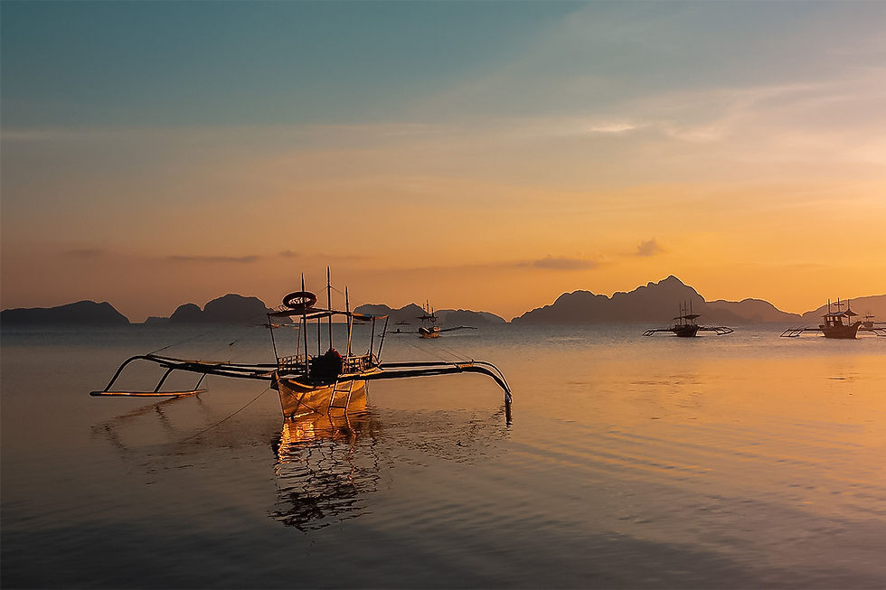 Ice Sun landscape photograph of an orange sunset over calm water, boats and distant mountains.