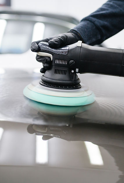 Car detailing - Man with orbital polisher in repair shop polishing car. Selective focus..j