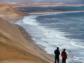Deux personnes debout au sommet d'une dune près de l'océan
