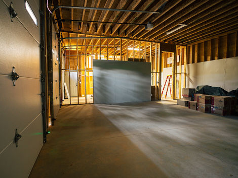 Unfinished garage loft with wood framing, windows, and stairwell opening