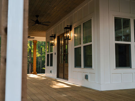 Custom covered porch with wood decking, ceiling fans, and exterior lantern lighting