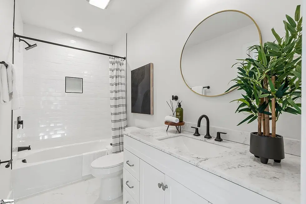 Remodeled bathroom with white vanity, marble countertop, bathtub, and modern fixtures