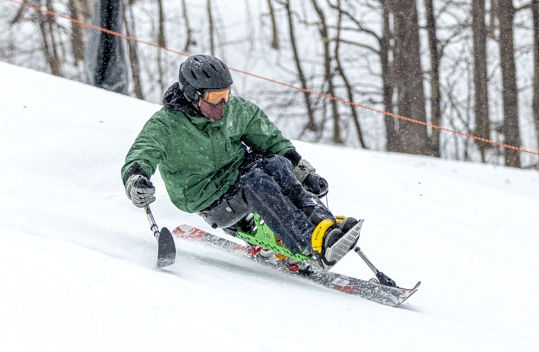 Adaptive skier descending a ski slope.