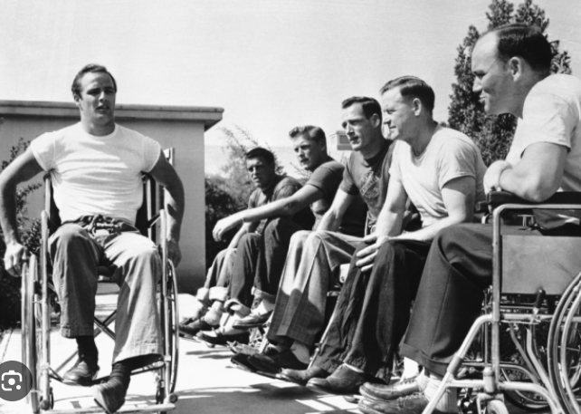 Man in wheelchair in front of other men in wheelchairs.