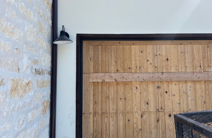 Seamless gutters installed on a modern garage with stone and wood features in Hutto, TX.