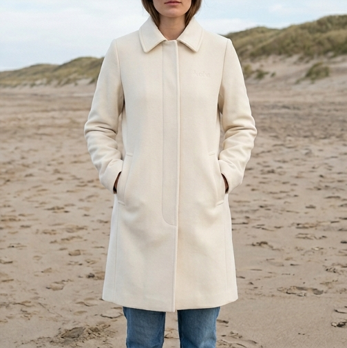 Woman in a cream wool coat on a sandy beach