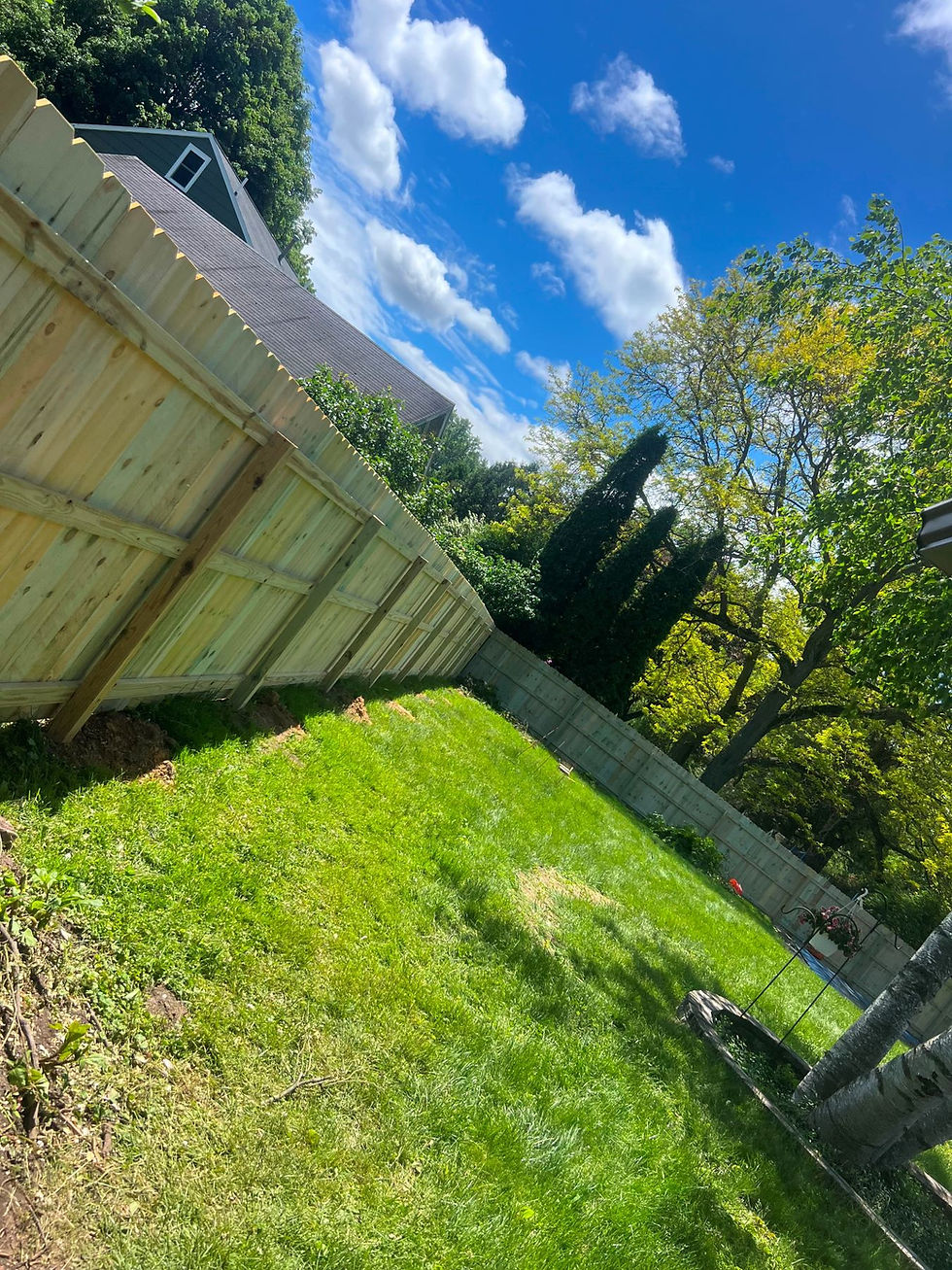 Sloped wooden fence along green hill Vertical wood privacy fence stretching across a steep