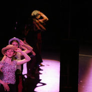 Three dancers manipulating their hats parade in front of a mirror