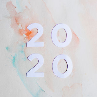 White "2020" on pastel watercolor background with splashes of orange and blue, creating a calm and artistic mood.