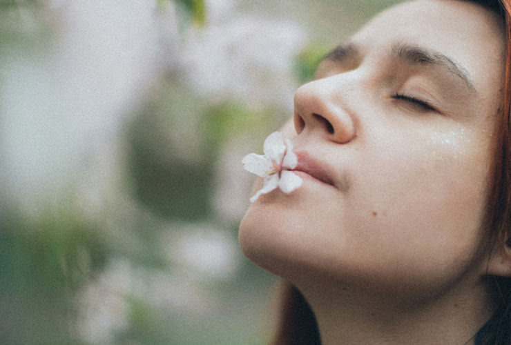 Relaxed person holding a cup of tea, smiling, looking out a window, representing a peaceful smoke-free lifestyle