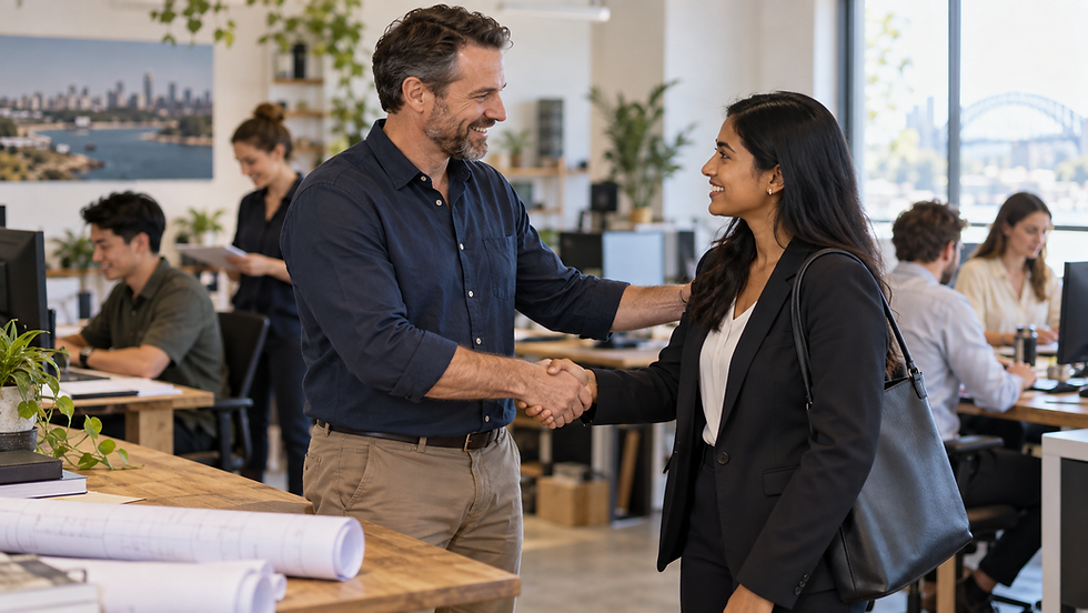 A small business owner welcoming an overseas specialist to an active workplace with local colleagues working in the background in Australia