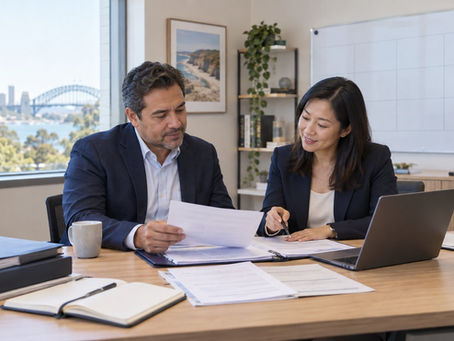 An experienced international professional comparing original career records with an adviser in a modest office with a plain unmarked planning board in Australia