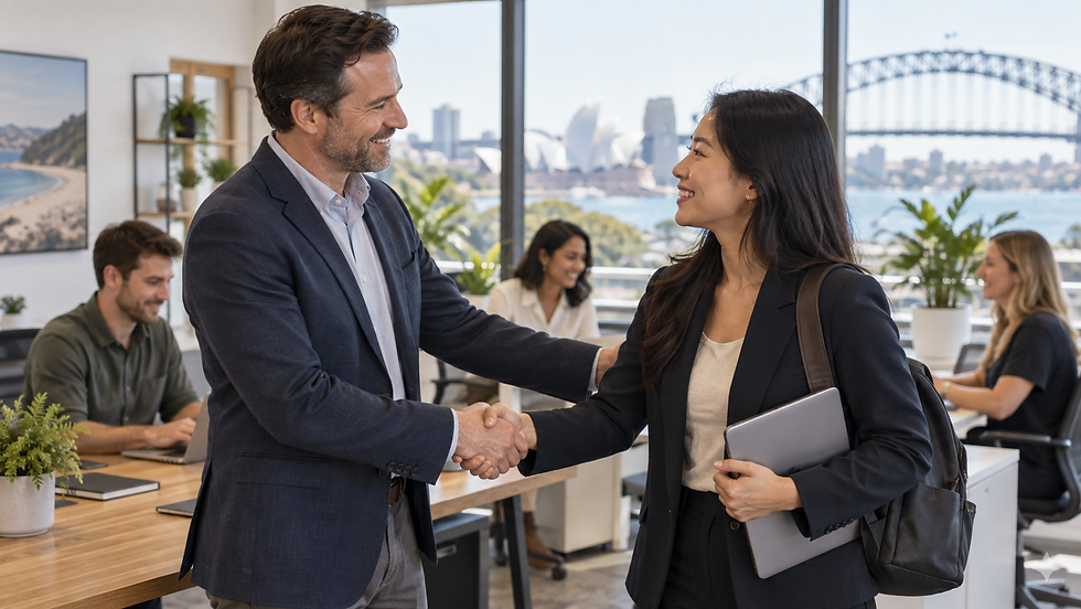A small business owner welcoming an overseas specialist to an active workplace with local colleagues working in the background in Australia