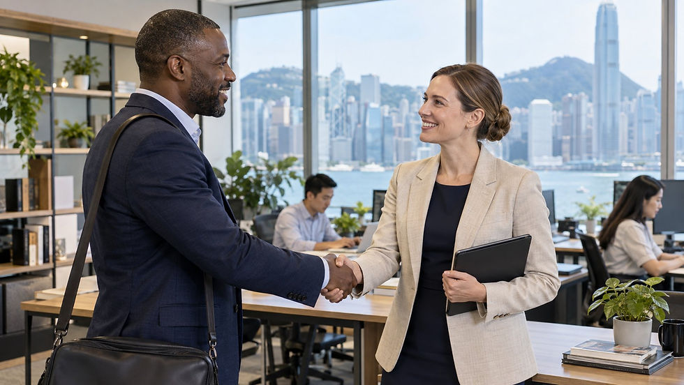 A small business owner welcoming an overseas specialist to an active workplace with local colleagues working in the background in Hong Kong