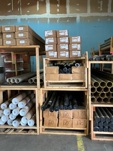 Industrial warehouse shelves stocked with pipes, rods, and various materials, showcasing a clean and organized storage space.