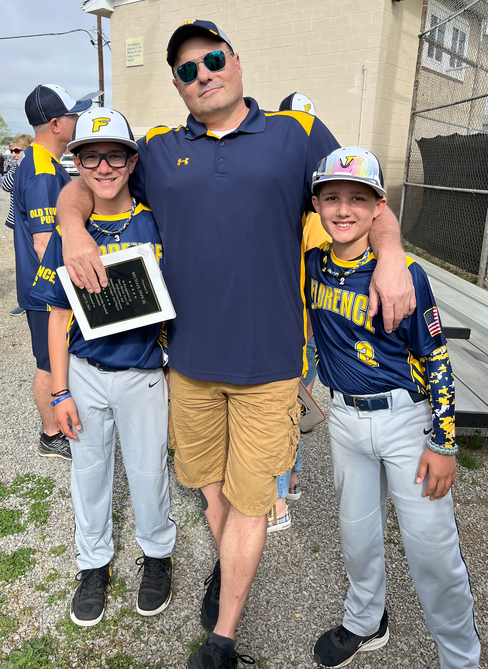 Mike Pepe standing with two young Florence Township baseball players, smiling and holding a plaque during Opening Day celebrations.