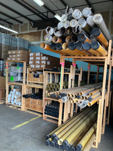 Industrial warehouse shelves stocked with pipes, rods, and various materials, showcasing a clean and organized storage space.