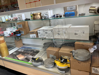 A close-up of industrial equipment and parts displayed in a glass case, featuring valves, fittings, and related products.