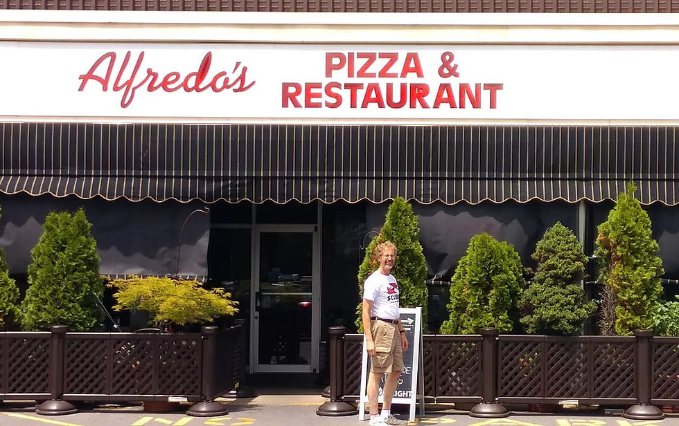 A man standing outside Alfredo's Pizza & Restaurant