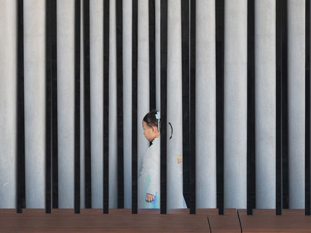 Double exposure shot of a small child passing by a concrete wall in Hong Kong