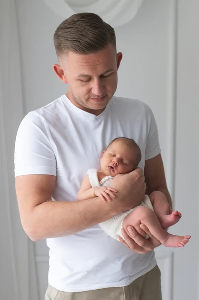 piękne ujecie taty trzymającego noworodka