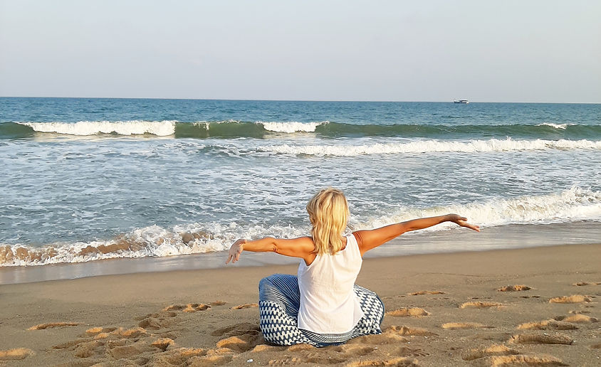 Blonde Frau am Strand mit ausgestreckten Armen