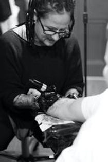 Tattoo artist working on tattoo on man's arm
