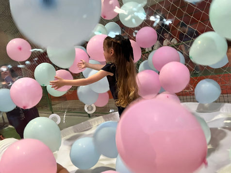 Criança sorrindo e pulando dentro da Bolha Mágica (Bubble House) da Festalize, rodeada por balões flutuantes.