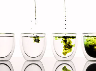gocce di clorofilla che cadono dentro a un bicchiere di acqua