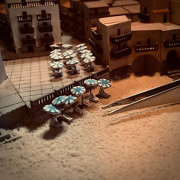 Placing miniature beach umbrellas on the diorama.