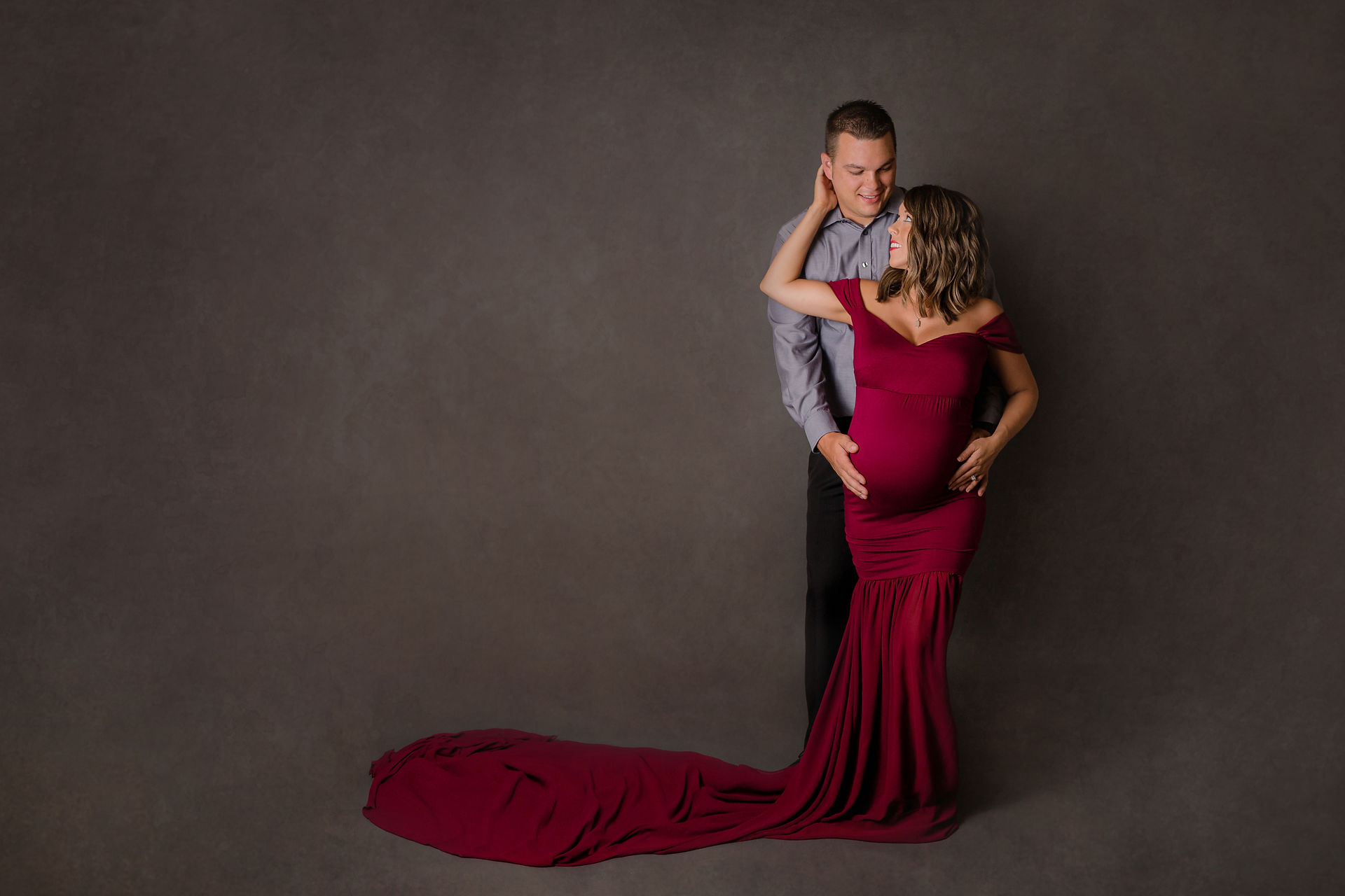 pregnant woman in a red gown looking back at her husband