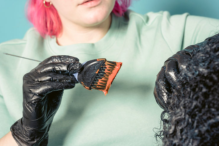 cabeleireira aplicando com luva e pincel tintura em cabelo