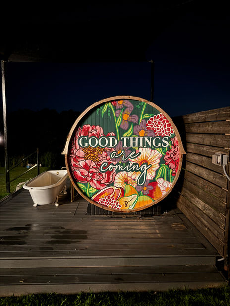Colorful, floral mural painted on an outdoor sauna  that says "Good things are coming"