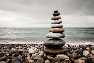 A balanced stack of 9 stones on a stony beach - water to horizon.