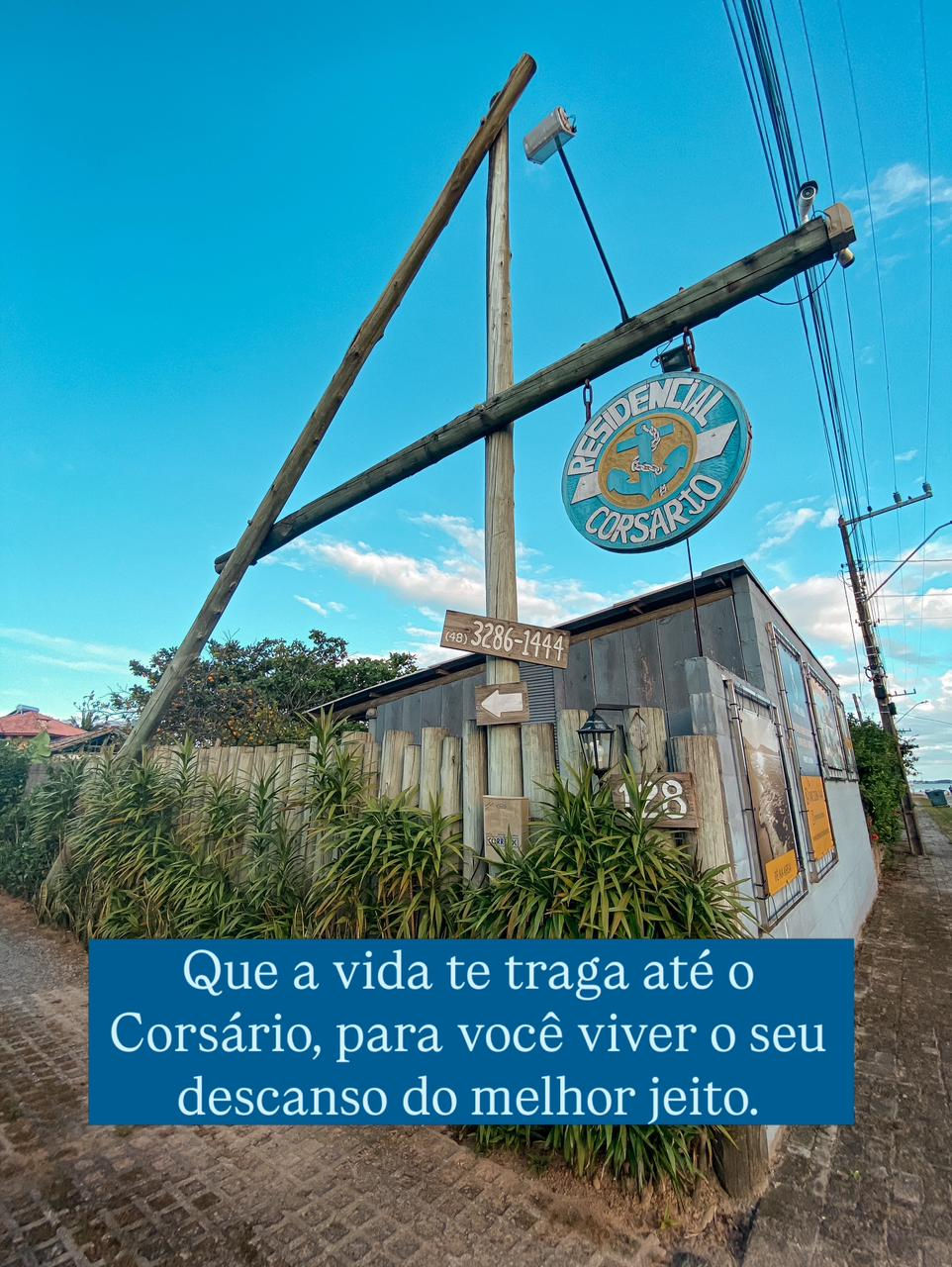Entrada do Residencial Corsário na Ponta do Papagaio, com placa de identificação, vegetação e acesso à hospedagem.