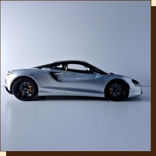 Thumbnail: Zilverkleurige sportwagen op een effen achtergrond. Zwart dak en velgen.