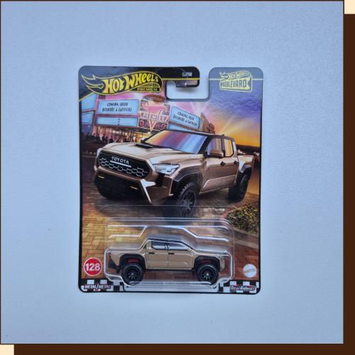 Thumbnail: Hot Wheels Tacoma truck, gold and black with card packaging, on display.
