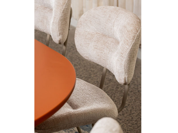 Merriton Dining Chair with beige upholstery near orange table