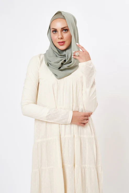 Single woman wearing modest clothing, including a long-sleeved, high-neck blouse, a flowing maxi skirt, a lightweight cardigan, and a stylish scarf