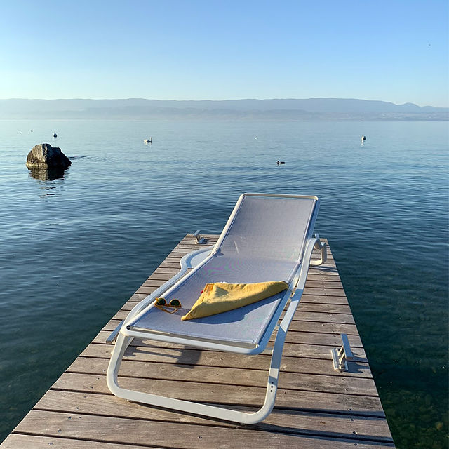 EGO Paris Marumi Sunlounger with a pillow, on a wooden deck in the sea