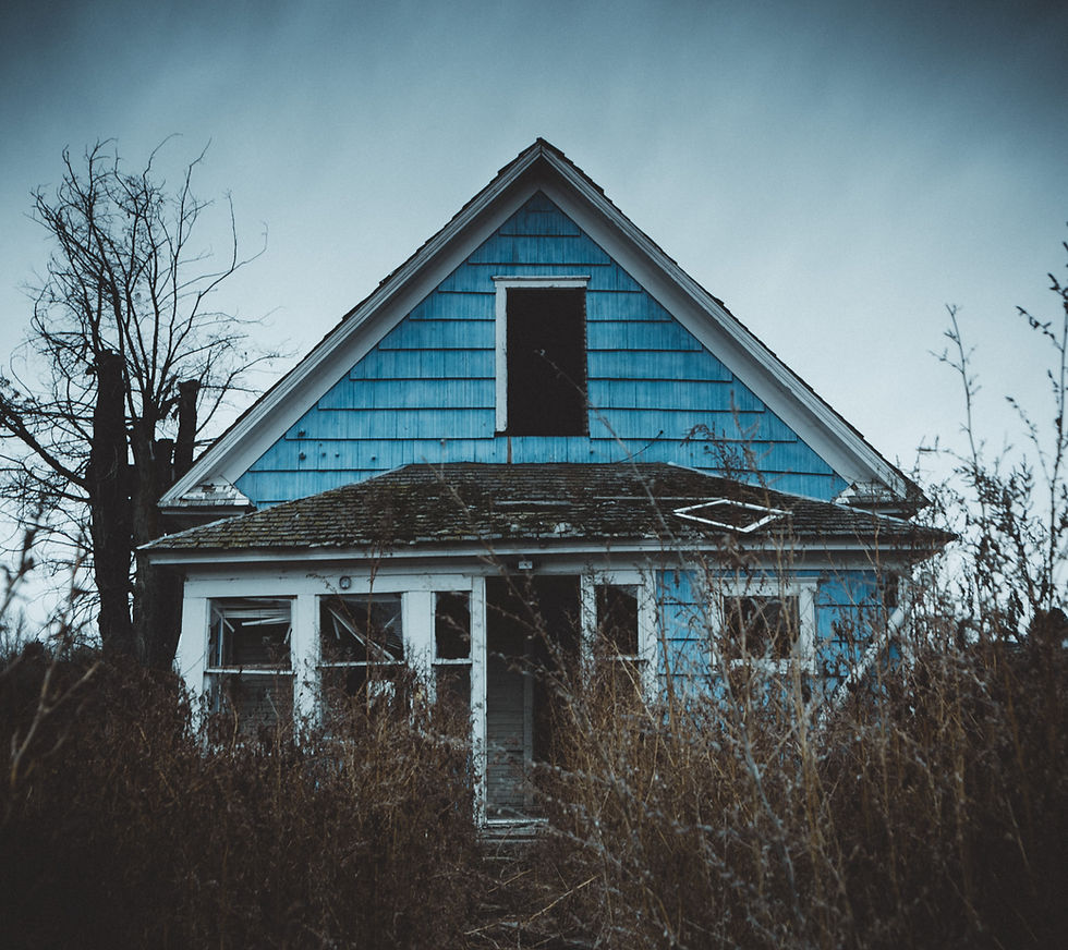 Eye-level view of a damaged house exterior with peeling paint and broken windows